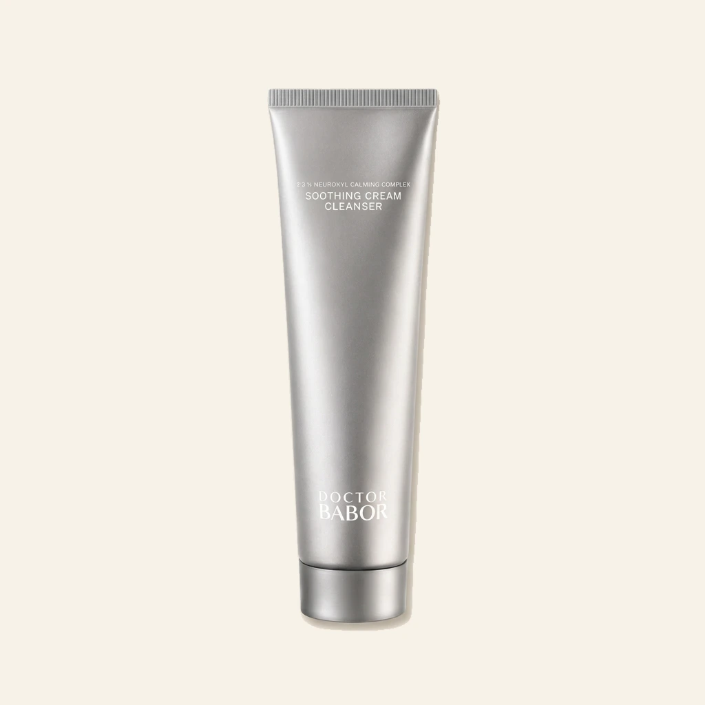 DOCTOR BABOR Soothing Cream Cleanser in silberner Tube vor modernem Spa-Hintergrund mit sanften Beige- und Naturtönen. Hochwertige Beauty-Produktinszenierung mit cleanem Luxus-Look, weichem Licht und entspannender Wellness-Atmosphäre