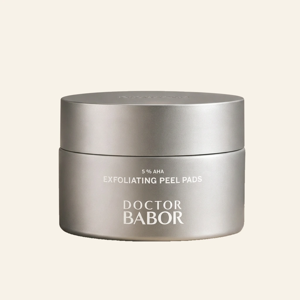DOCTOR BABOR 5% AHA Exfoliating Peel Pads in elegantem silbernen Tiegel vor modernem Spa-Hintergrund mit warmen Beige- und Naturtönen, Naturstein und stilvollen Wellness-Elementen. Hochwertige Beauty-Produktinszenierung mit cleanem Luxus-Look und entspannender Spa-Atmosphäre