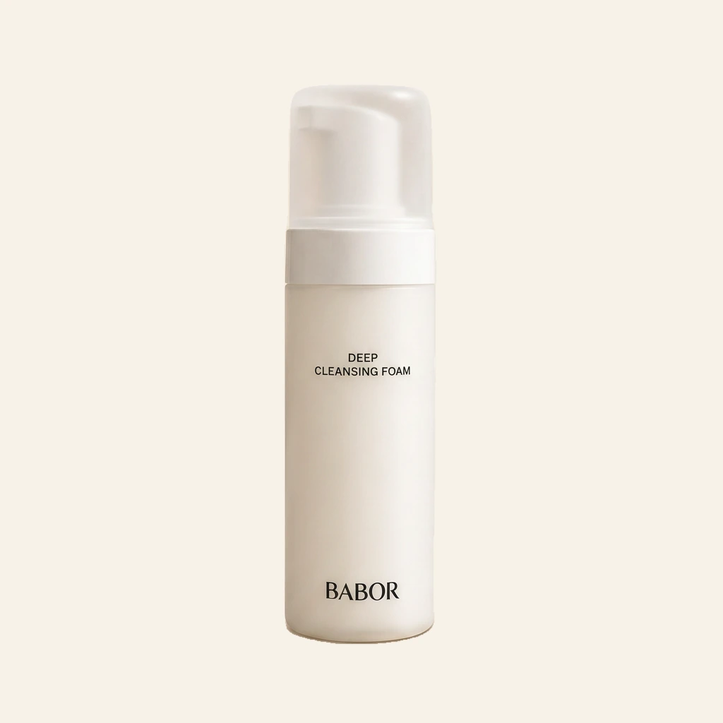 BABOR Deep Cleansing Foam in eleganter weißer Pumpflasche vor warmem Spa-Hintergrund mit Naturstein, sanften Beige- und Cremetönen, Kerze und grünen Blättern. Hochwertige Beauty-Produktinszenierung mit cleanem Luxus-Look und entspannender Wellness-Atmosphäre