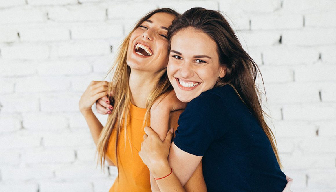 Zwei Frauen, die sich umarmen und zusammen lachen