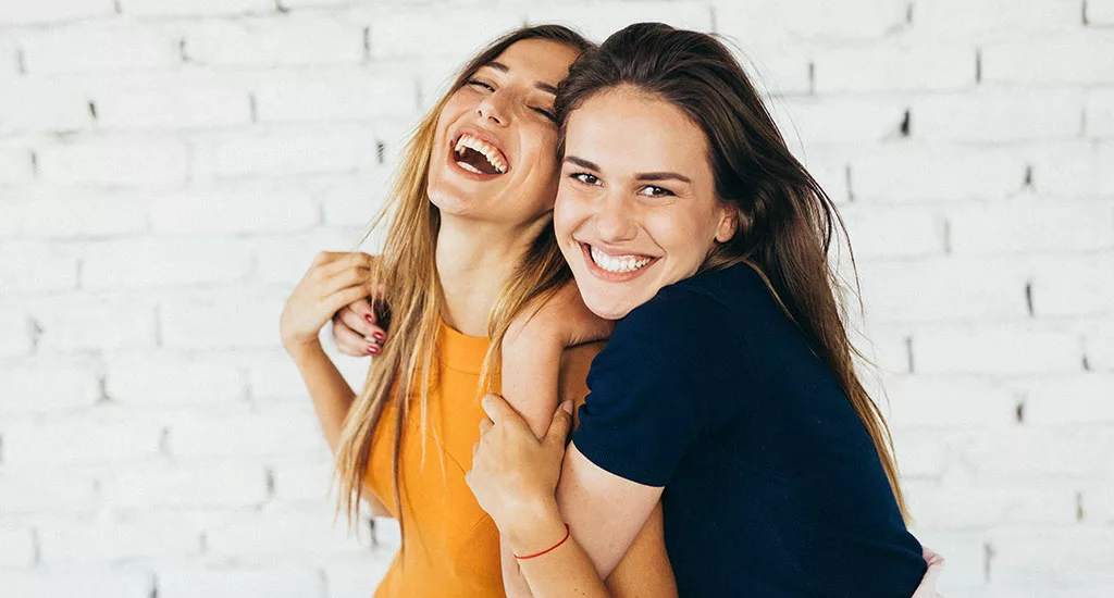 Zwei Frauen, die sich umarmen und zusammen lachen