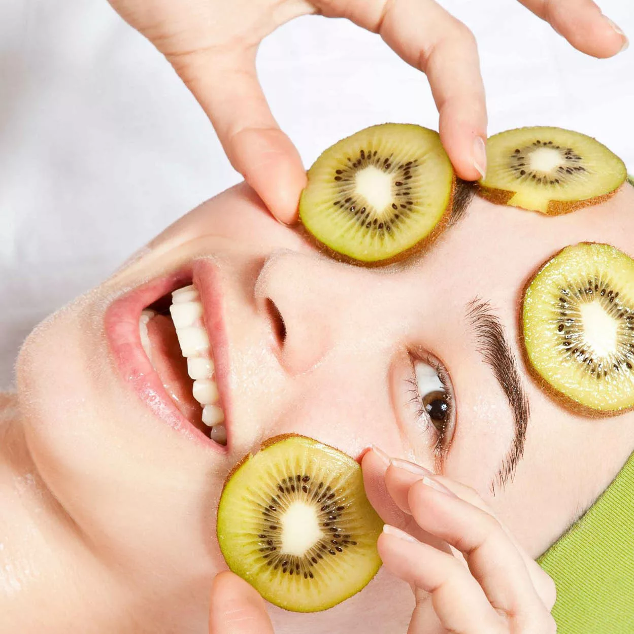 Frau mit Kiwi Scheiben im Gesicht